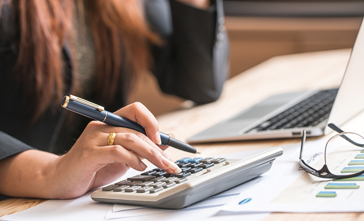 Women Calculating With Calculator And Laptop