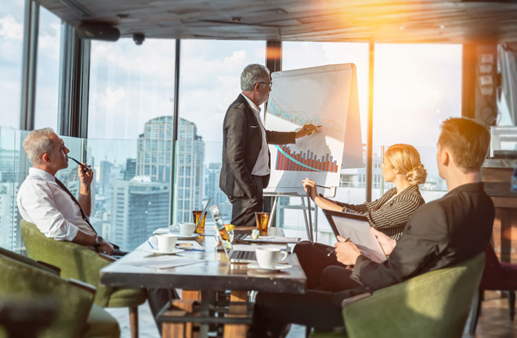 4 colleagues having a meeting in a room with a view of the skyline.