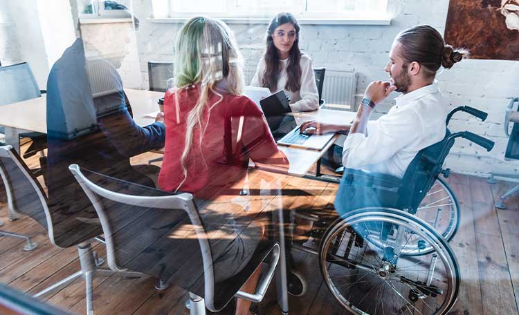 A group of diverse colleagues including a man in a wheel chair in the conference room