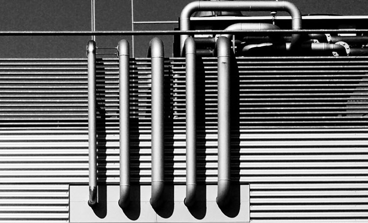 black and white industrial building exterior with exposed pipes