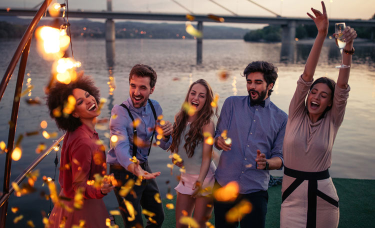young western party goers on a beach, bridge in background