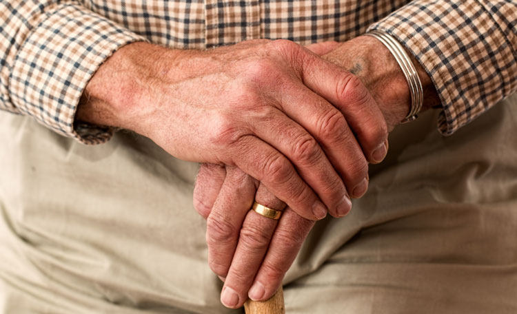 elderly gentleman's hand place over each other on walking stick