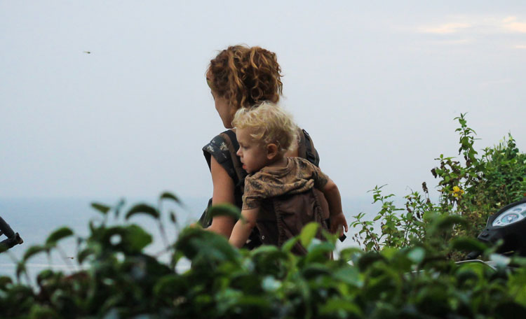 Mother walking in countryside with toddler on back
