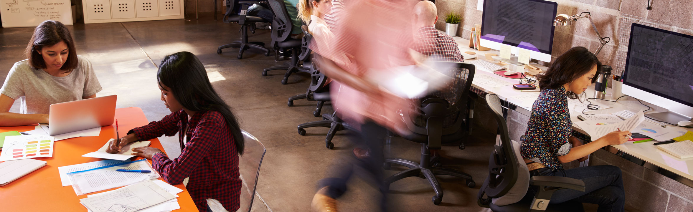 workers in coworking space blurred man walking past seated women