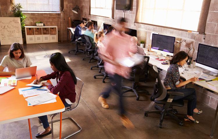 workers in coworking space blurred man walking past seated women